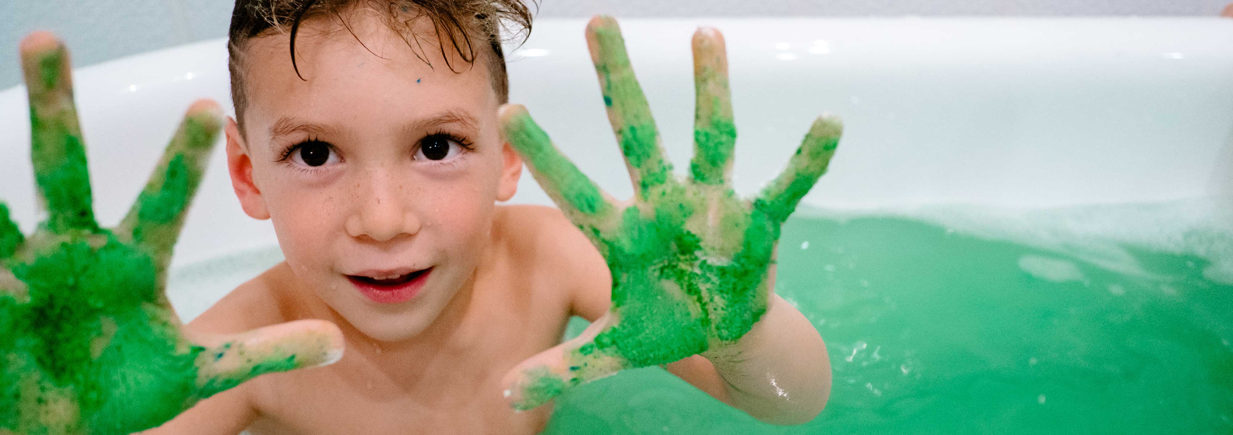 Kid enjoying Bubble Whoosh in tub, green water for playful bath time fun.